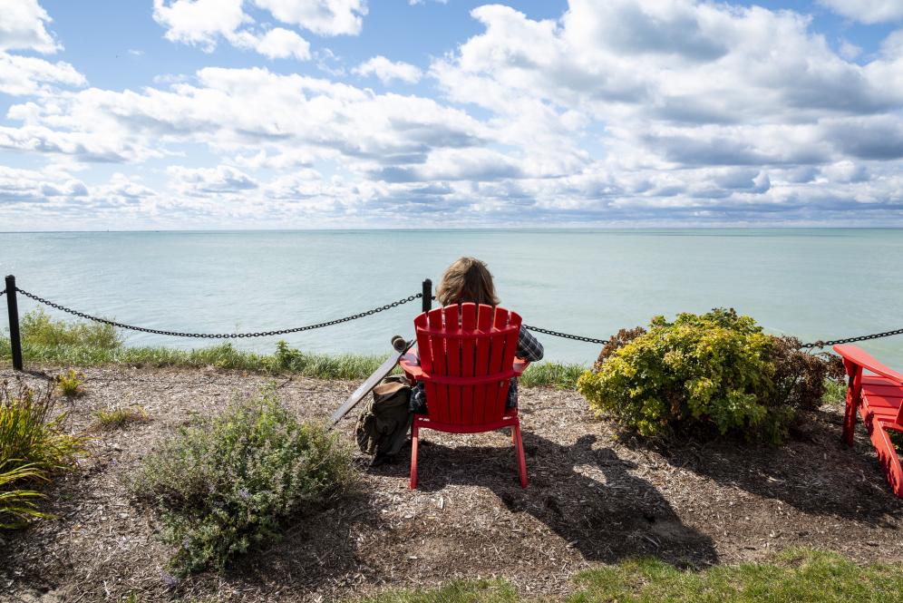 一名学生在密歇根湖边的一把红椅子上休息.