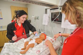 护理专业学生使用婴儿人体模拟器进行工作.